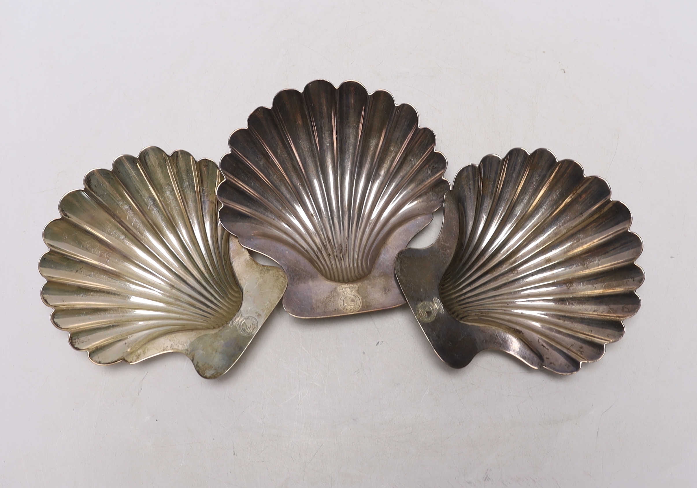 A set of three George III silver butter shells, each with engraved crest and on two shell feet, by Robert Garrard I, London, 1803, 12.8cm, 9.7oz.